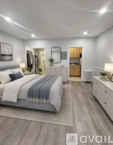 A well-lit bedroom with a large bed, a dresser, and a mirror.