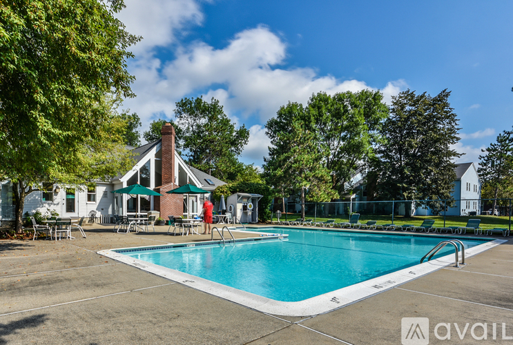 A swimming pool surrounded by trees and a building in the background.