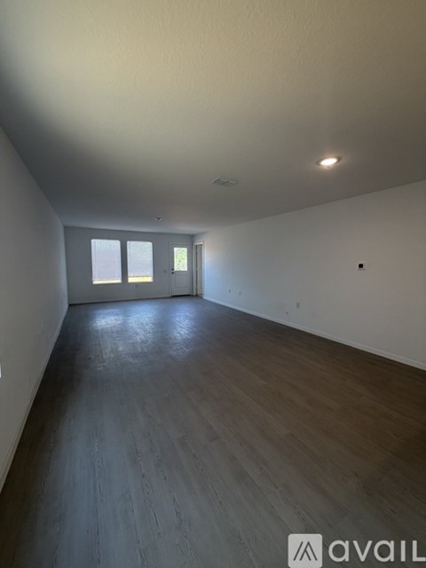 A spacious room with wooden floors and a doorway leading to another room.