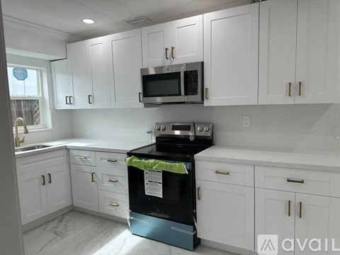 A kitchen with white cabinets and a black stove top oven.
