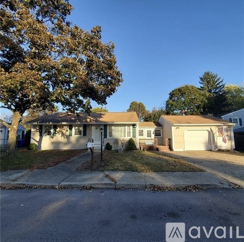 A house with a driveway and a tree in front.