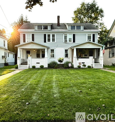 A large white house with a porch and a sign that says "available".