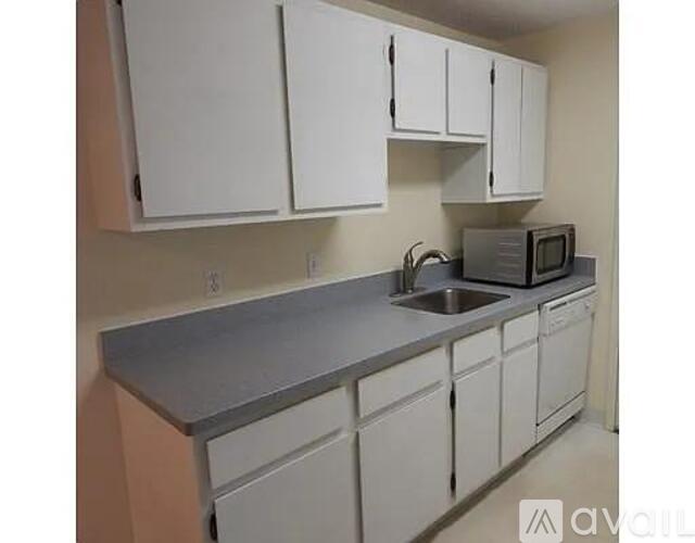 A kitchen with white cabinets and a stainless steel counter.