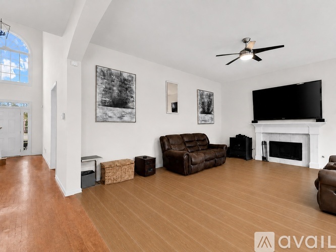 A living room with a brown leather couch and a fireplace.
