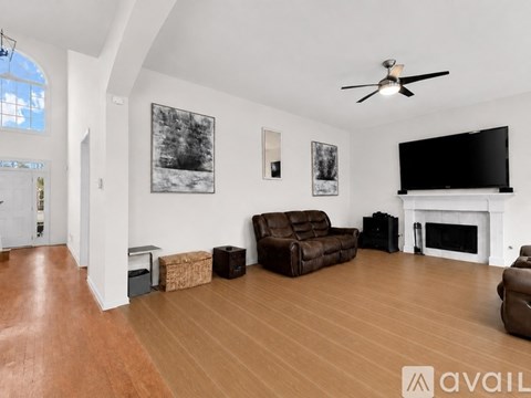 A living room with a brown leather couch and a fireplace.