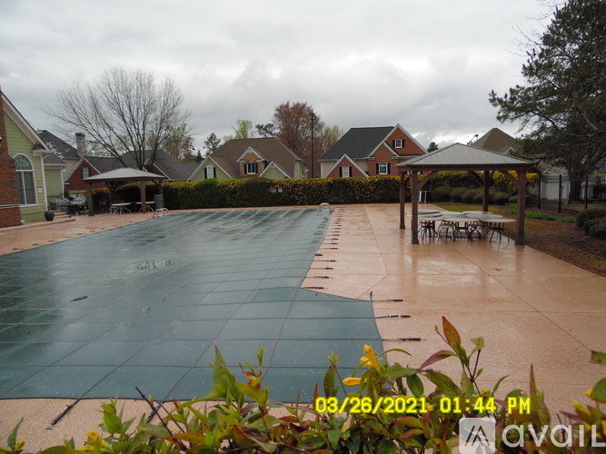 A pool surrounded by a green cover and a patio with chairs.