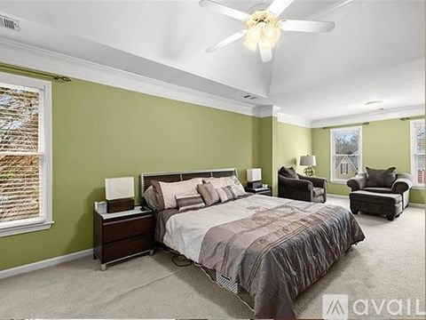 A bedroom with a large bed and a ceiling fan.
