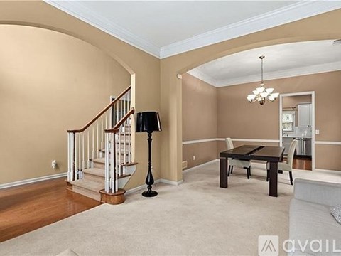 A living room with a staircase and a lamp.