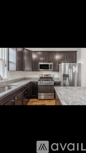 A kitchen with dark brown cabinets and stainless steel appliances.
