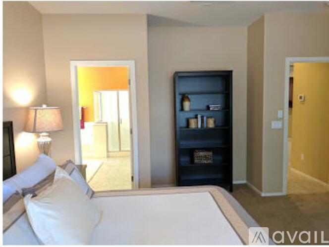 A bedroom with a bed, a lamp, and a bookshelf.