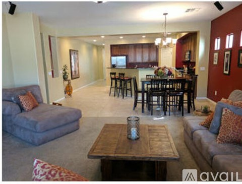 A living room with a grey couch, a wooden coffee table, and a dining table with chairs.