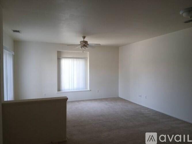 A room with a ceiling fan and a window with blinds.