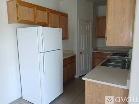 A white refrigerator in a kitchen with wooden cabinets.