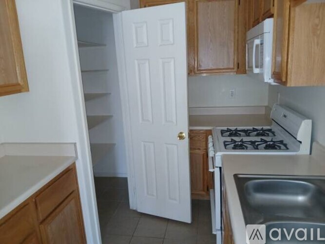 A kitchen with a white door, a stove, and a sink.