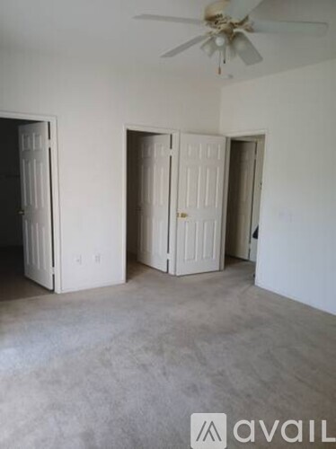 A room with a ceiling fan and three doors.