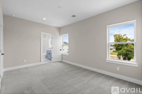 A spacious room with a carpeted floor and a window showing a tree and sky.
