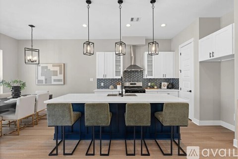 A modern kitchen with a large island and chairs.
