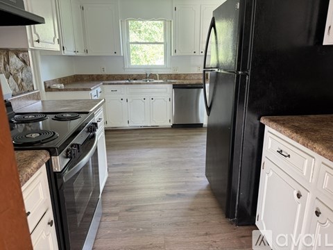 A kitchen with a black refrigerator and white cabinets.