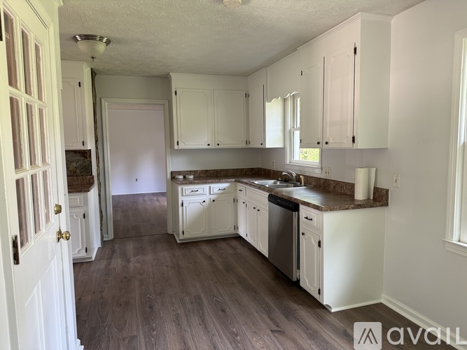 A kitchen with white cabinets and a wooden floor.