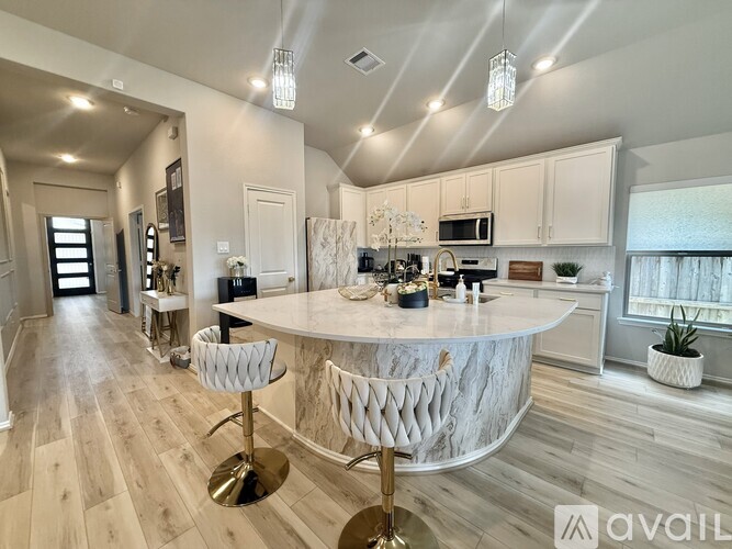 A modern kitchen with a marble island and bar stools.