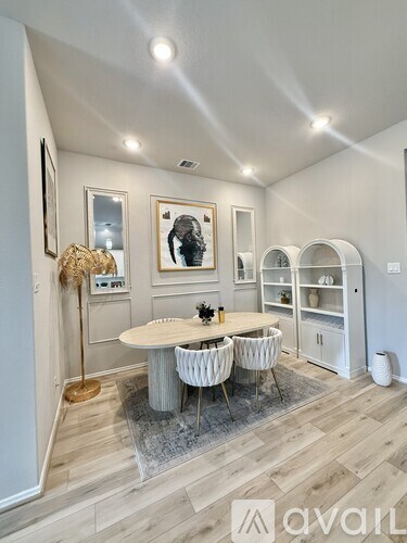 A dining room with a round table and chairs, a rug, and a wall-mounted shelf.