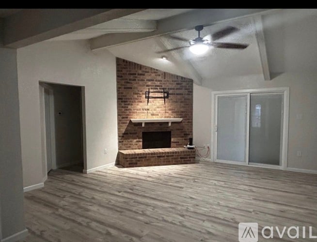 A room with a brick fireplace and wooden flooring.