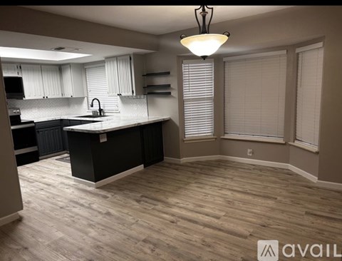 A kitchen with a black countertop and wooden flooring.