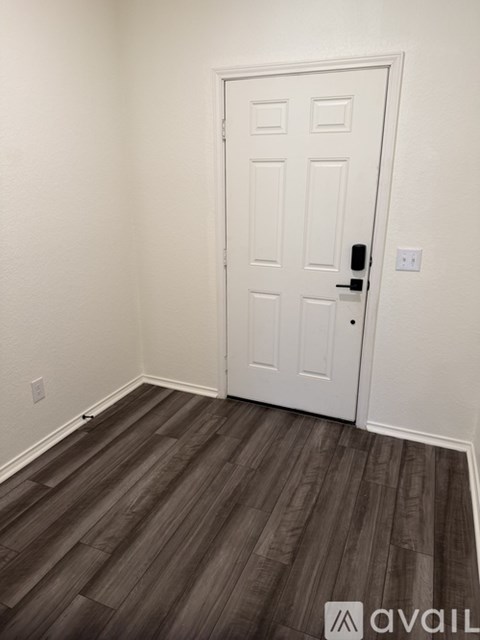 A white door with a black handle is in a room with wooden flooring.