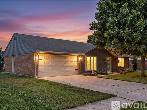 A house with a garage and a tree in front of it.