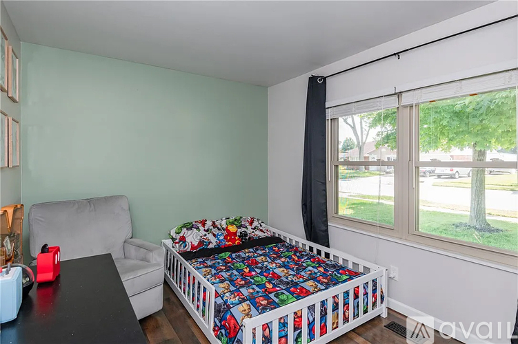 A bedroom with a bed covered in a colorful blanket and a white couch.