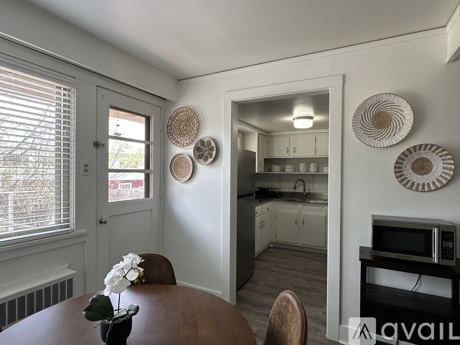 A kitchen with a table and chairs in the foreground and a microwave on the counter.