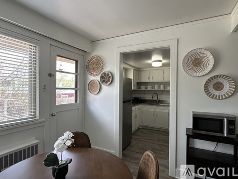 A kitchen with a table and chairs in the foreground and a microwave on the counter.