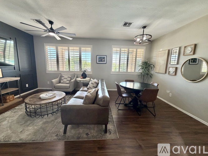 A living room with a brown sofa, a round table, and a fan on the ceiling.