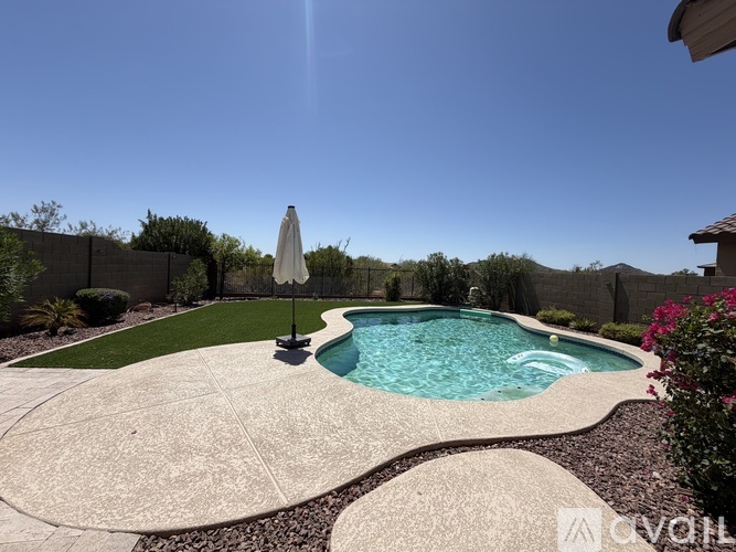 A pool with a white umbrella in the middle of a concrete patio.