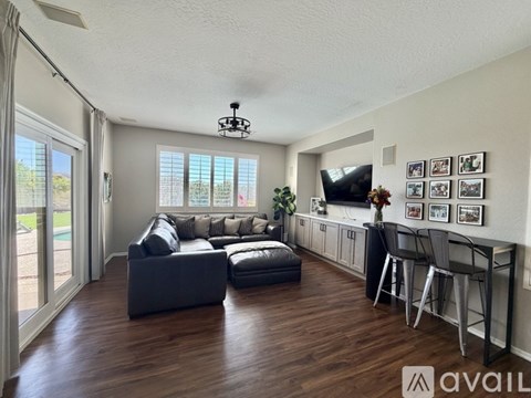 A living room with a grey couch and a television on the wall.