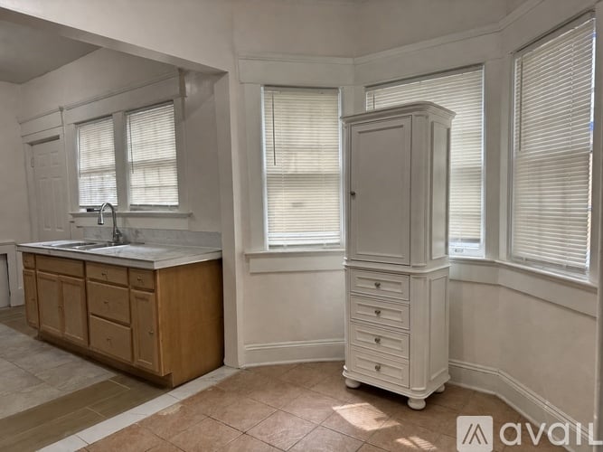 A kitchen with a sink, wooden cabinets, and a white cabinet with drawers.