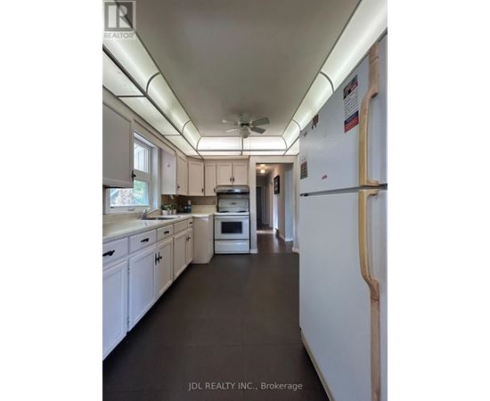 A kitchen with white cabinets and a white refrigerator.