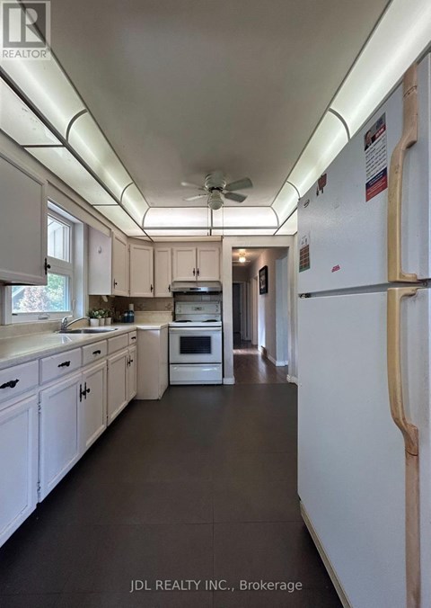 A kitchen with white cabinets and a white refrigerator.