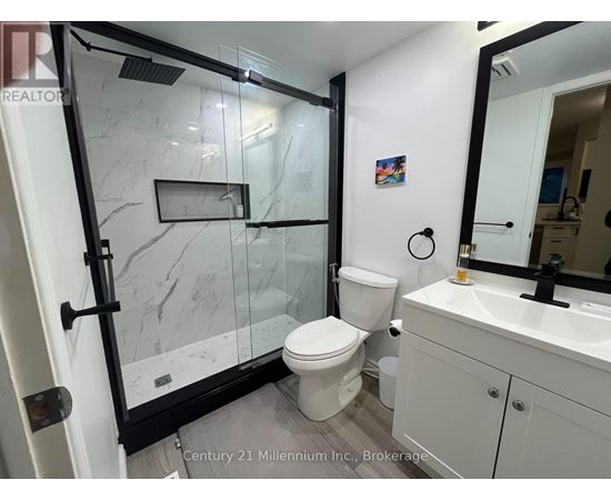A white toilet with a black handle is in a bathroom with a marble floor.