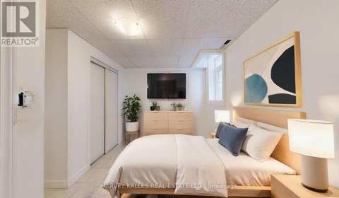 A well-lit bedroom with a large bed and a painting on the wall.