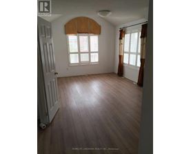 A room with wooden floors and a window with brown curtains.
