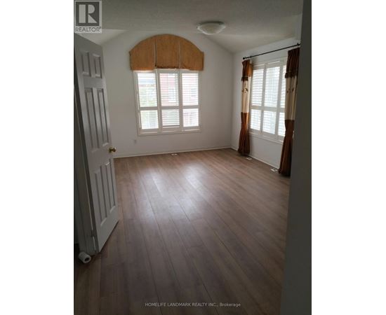 A room with wooden floors and a window with brown curtains.