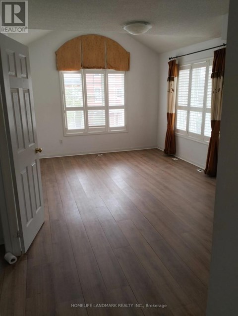 A room with wooden floors and a window with brown curtains.