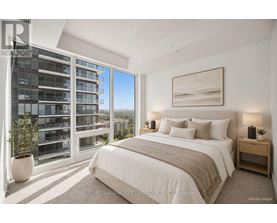 A bedroom with a large bed, a window with a view of a building, and a painting on the wall.