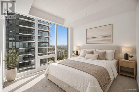 A bedroom with a large bed, a window with a view of a building, and a painting on the wall.