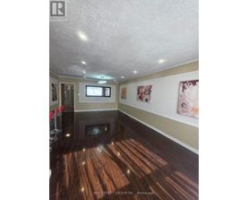 A spacious room with wooden floors and a television mounted on the wall.