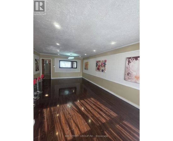 A spacious room with wooden floors and a television mounted on the wall.