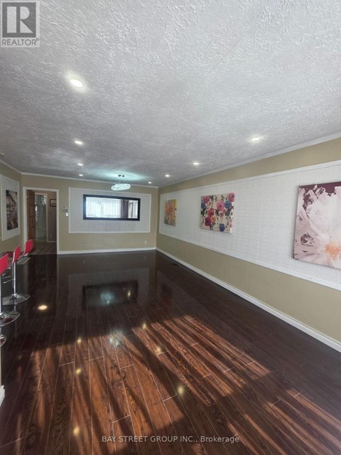 A spacious room with wooden floors and a television mounted on the wall.