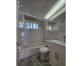 A white toilet sits in a bathroom with a white tub and sink.