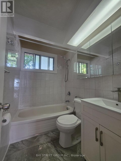 A white toilet sits in a bathroom with a white tub and sink.